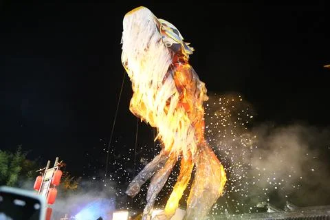 Tall glowing dragon puppet surrounded by smoke and sparkling particles in a.. Stock Photos