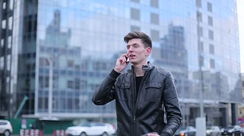 Tall guy talking on a mobile phone on the background of the business center Stock Footage 61429180