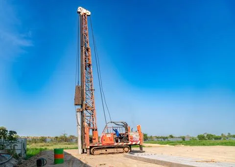 A tall hydraulic crawler piling rig stands sitioning a concrete pile. Stock Photos