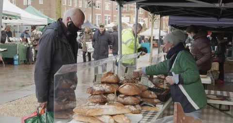 Tall man in face mask purchasing a loaf of bread, served by a female Stock Footage 150114286