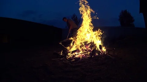 Tall Man Turning Burning Garbage In Large Bonfire on Cottage Backyard Video stock 74979214