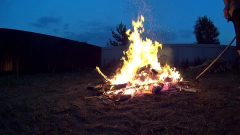 Tall Man Turning Burning Garbage In Large Bonfire on Cottage Backyard Stock Footage 74979720