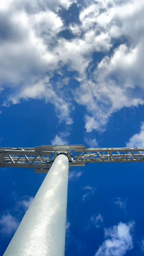 Tall metal communication tower viewed against blue sky with moving clouds Video stock 337104356