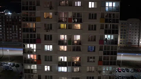 Tall multi-storey building in the evening. In the windows of apartments people Stock Footage 142267519