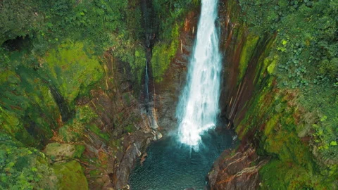 Tall narrow waterfall cascading down cliffside in Blue Falls Costa Rica forest Stock-Footage 326014162