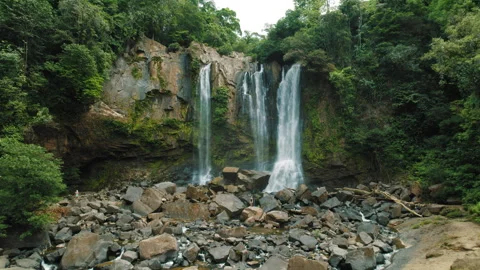 Tall Nauyaca waterfall cascading down rocky cliffs by dense jungle in Costa Rica Stock Footage 321559182