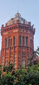A tall, octagonal tower of red brick with a dome roof and numerous arched win Stock Photos