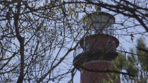 Tall Red and White Lighthouse Seen Through Forest Trees Vídeo Stock 74401437