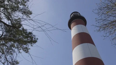 Tall Red and White Lighthouse Below Clear Blue Sky Vídeo Stock 74401697