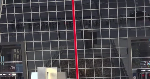 A tall red pole is in front of a building with a lot of windows Stock-Footage 327320222