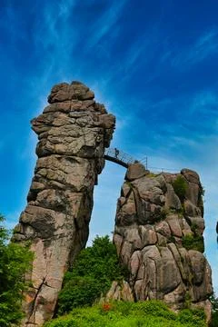 Tall rock formations with bridge high above a green landscape on a sunny day Stock Photos