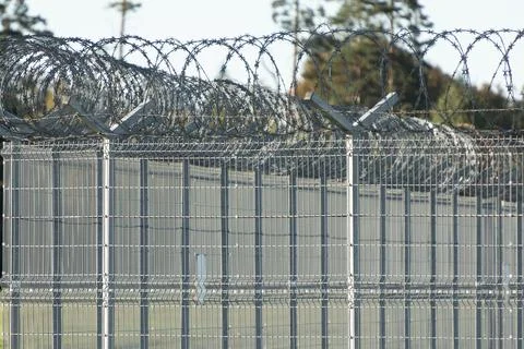 Tall security fence topped with multiple coils of razor wire, layered metal.. Stock Photos