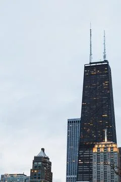 A tall skyscraper rises in Chicago with cloudy skies above. Nearby buildings  스톡 사진