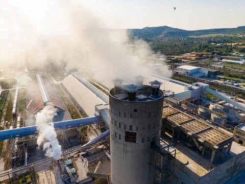 A tall smoke stack is seen releasing steam and smoke as machinery operates in Foto stock