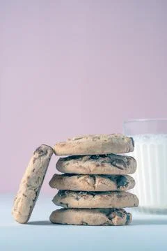 A tall stack of chocolate chip cookies with a glass of milk in the background 스톡 사진