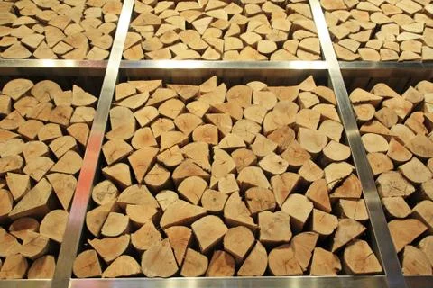Tall stack of firewood logs on iron storage Stock Photos