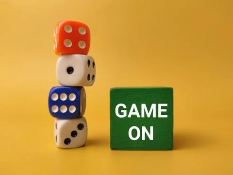 A tall stack of four colorful game dice stands next to a green block with t.. 库存照片