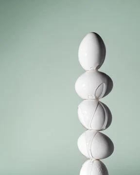 A tall stack of white eggs with transparent paint dripping down their surface Stock Photos