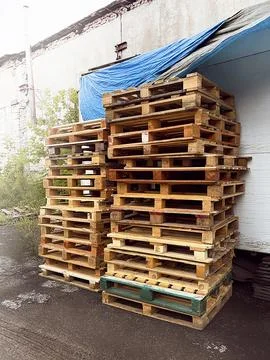 Tall stack of wooden pallets stored outside, vertical photo Stock Photos