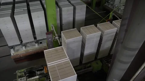 Tall stacks of unfired tiles are loaded onto kiln car platforms inside a Stock Footage 346737783