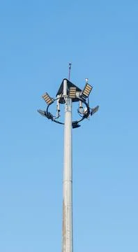 A tall stadium light pole with multiple lamp fixtures stands against a clea.. Stock Photos