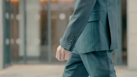 A tall, thin man in a gray elegant suit walks down a city street. Video stock 226355225