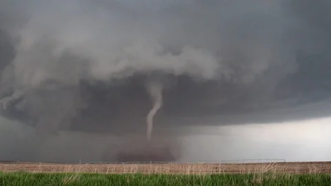 A tall thin tornado with dust cloud underneath a dark storm Stock Footage 108421299