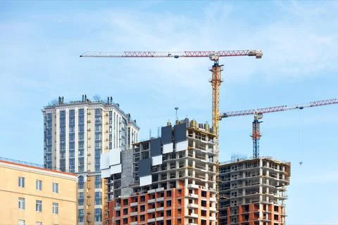 Tall tower cranes on the construction of a monolithic frame concrete structur Stock Photos
