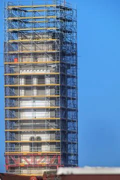Tall tower undergoing extensive renovation with scaffolding against a clear.. Fotos de archivo