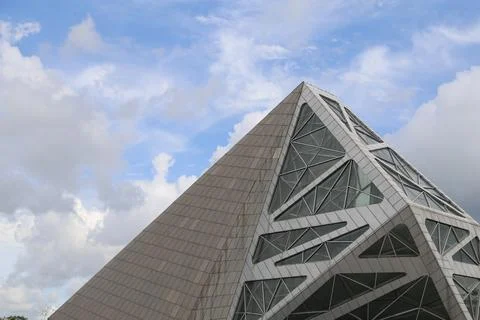 A tall, triangular building with angular lines and large windows against th.. Stock Photos
