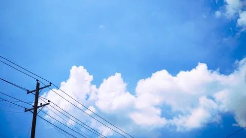 Tall utility pole with electrical wires standing against bright blue sky an.. Stock Photos