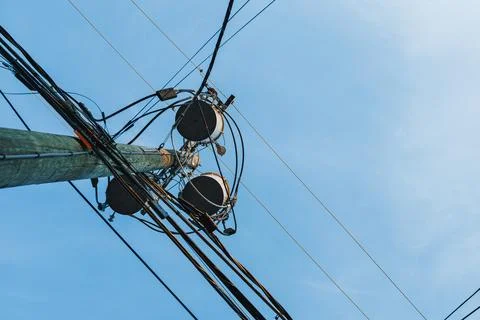 A tall utility pole has multiple wires and equipment attached, reaching up in Photos