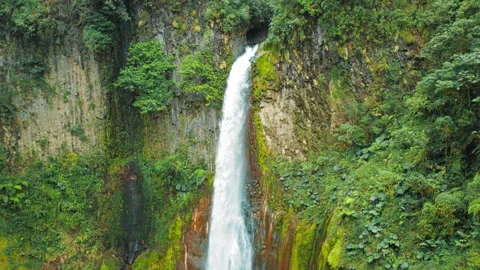 Tall waterfall pouring down mossy cliff into clear pool in Costa Rica Stock Footage 311490213