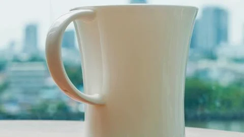 Tall white ceramic pitcher on a table with city view Stock Photos