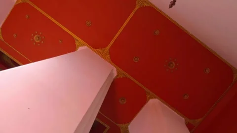 Tall white columns support a red ceiling with lamps in an Asian temple Stock Footage 308863640