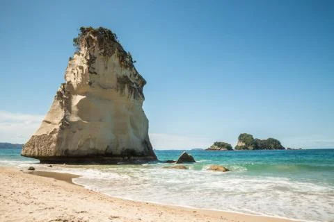 Tall white sea stack above sandy beach in New Zealand Stock Photos