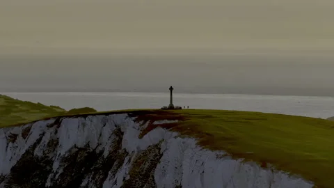 A tall white tower is on a hill overlooking the ocean Stock Footage 298292623