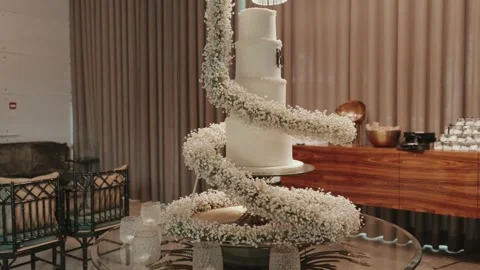 Tall White Wedding Cake with Spiral Gypsophila Garland on a Rotating Table Stock Footage 343697429
