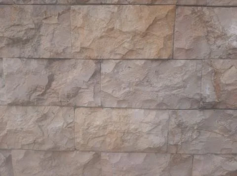 Tan and brown stone bricks create a textured wall surface, perfect for backgr Stock Photos