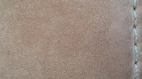 Tan suede leather texture surface with a thick white stitched seam Stock Photos