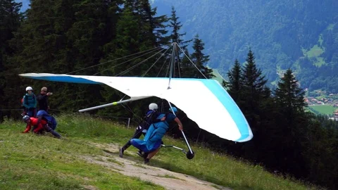 Tandem hang-glider taking off at Wallberg bavarian alps Tegernsee below Stock Footage 100534375