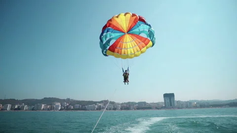 Tandem parasiling high against the clear blue summer sky. Parasailing in the  Vídeo Stock 190419912