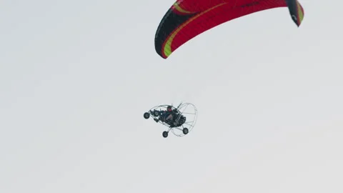 Tandem powered paraglider flight under red black canopy Stock Footage 317149202