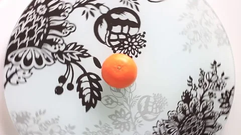 Tangerine in center of a rolling plate Stock Footage 71983293