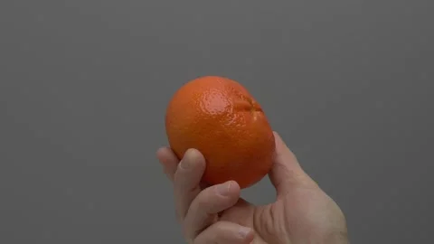 Tangerine in hand on a gray background. Stockbeeldmateriaal 265758151