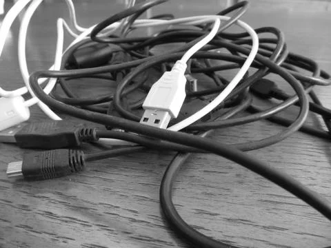 Tangle of dusty computer cables with sockets on the table . Black and white Stock Photos