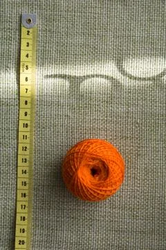 Tangle of orange thread and a measuring tape on a green cloth Stock Photos
