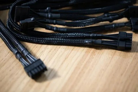 Tangled black computer cables lying on a brown wooden table 写真素材
