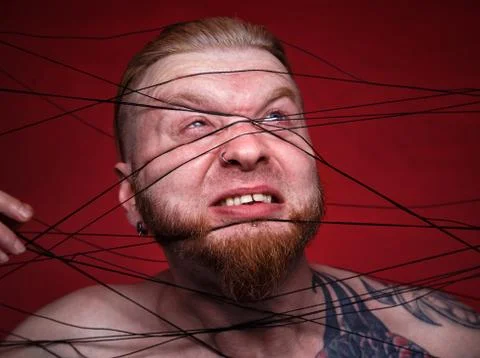 Tangled in black threads bearded man on red background Stock Photos