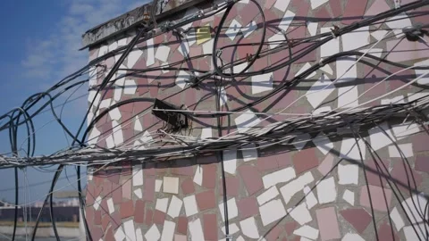 Tangled Communication Cables Hanging on Retro Mosaic Wall Exterior Stockbeeldmateriaal 347537540